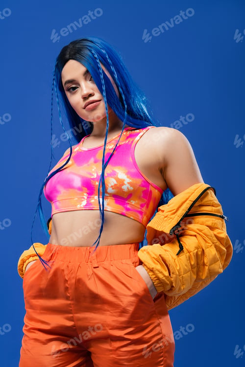 Preview: colorful clothes, dyed hair, female model with blue hair posing with hands in pockets