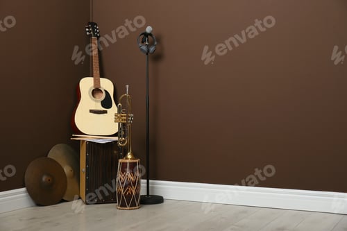 Preview: Set of different musical instruments and microphone near brown wall indoors, space for text