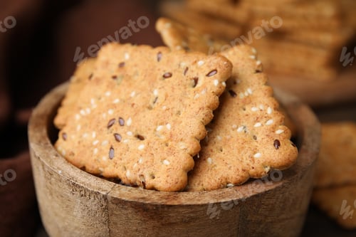 Preview: Cereal crackers with flax and sesame seeds in bowl on blurred background, closeup