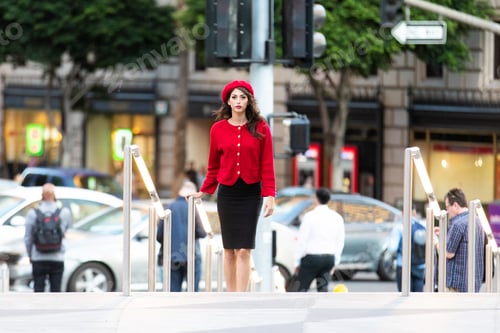 Preview: Pretty French woman wearing red beret and sweater outside in city