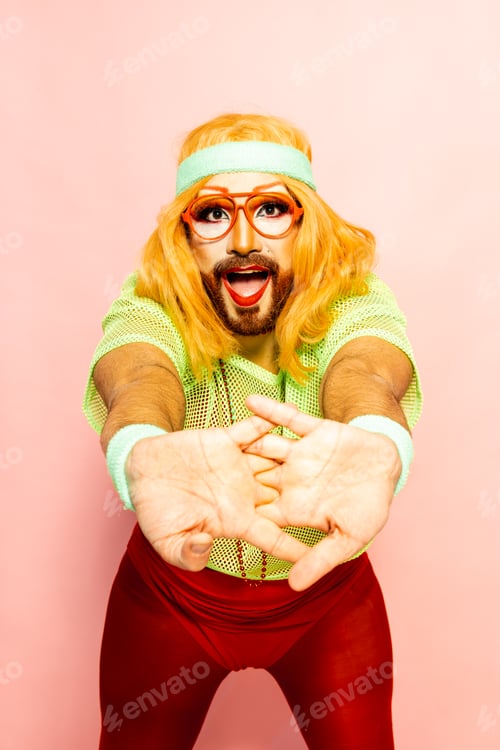 Preview: Vivacious Drag Queen in a Retro 80s Fitness Outfit Warms Up Against Pink Backdrop