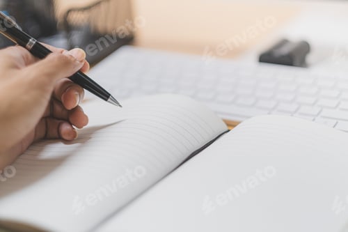 Preview: Close-up hand holding pen and write on white book