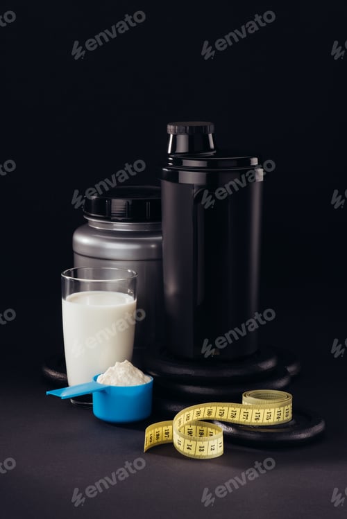 Preview: protein shaker with glass of white liquid and measuring tape isolated on black