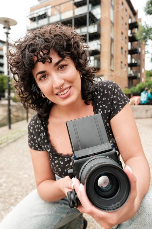 Preview: Photographer smiling and holding medium format camera in urban setting