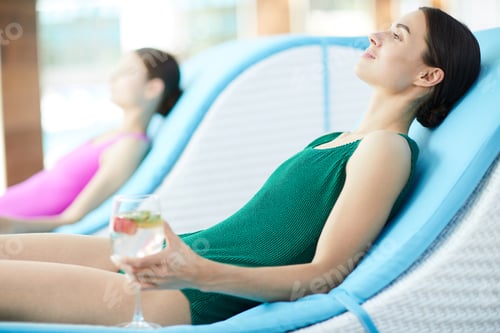 Preview: Two Women Relaxing on Loungers with Drinks