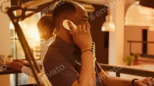 Preview: Business man answering landline phone call in office with big windows