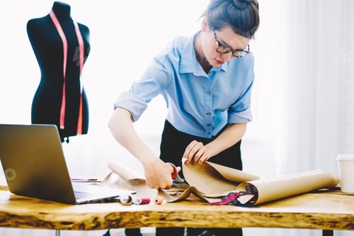 Preview: Young seamstress cutting out paper patterns