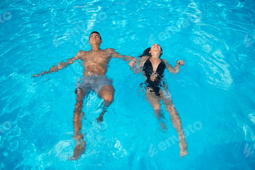 Preview: Couple in love refreshing in the swimming pool on the turquoise water at vacation.