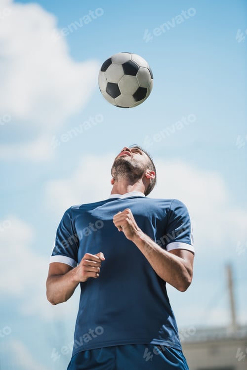 Preview: low angle view of soccer player training with ball on soccer pitch