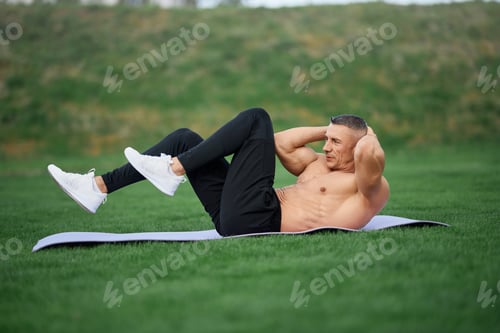Preview: Bodybuilder doing exercises for abs outdoors