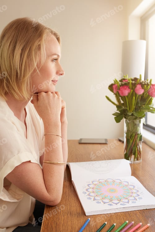 Preview: Thoughtful woman at a table with adult coloring book