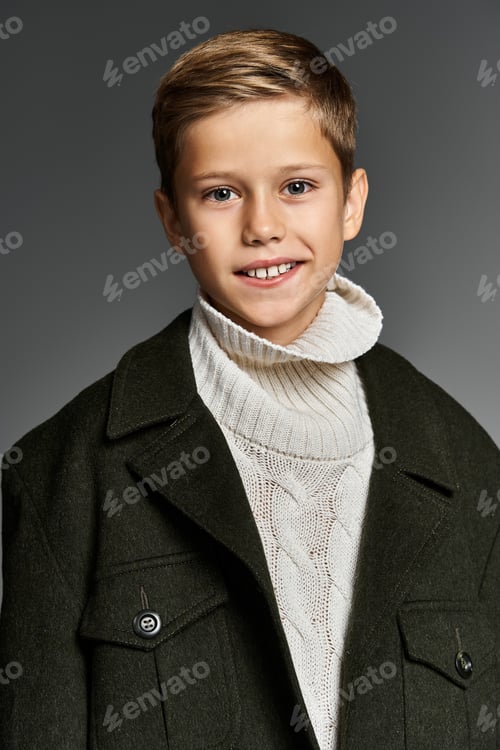 Preview: A young boy in cozy winter attire smiles warmly while posing against a soft background