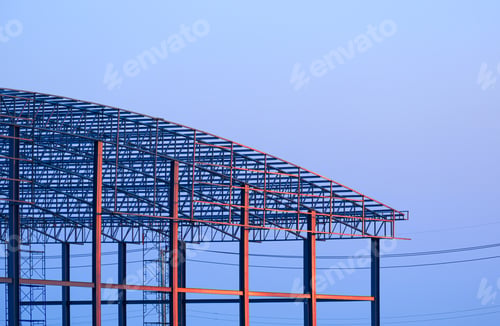Preview: Metal warehouse building with dome roof structure in construction site against blue evening sky