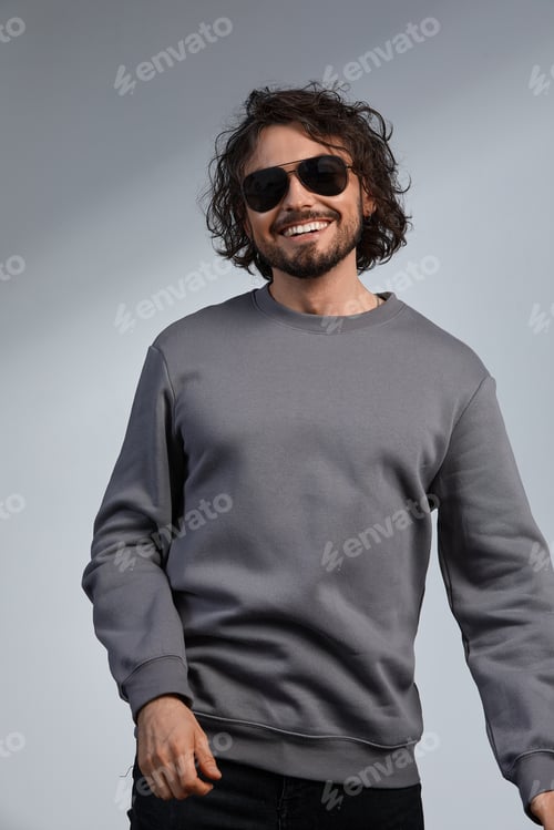 Preview: indoor portrait of handsome freckled smiling male with curly hair, wears sepctacles posing for