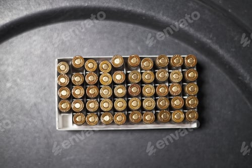 Preview: Box of Brass Ammunition Cartridges Arranged in Rows on Dark Background