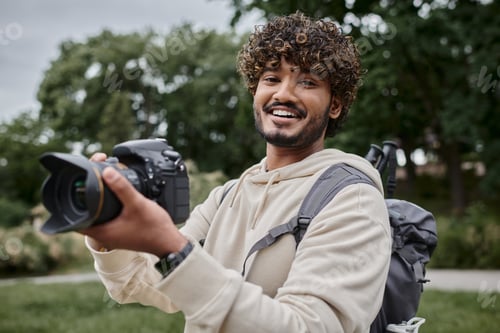 Preview: happy indian photographer with backpack taking photo on professional camera, adventure and travel