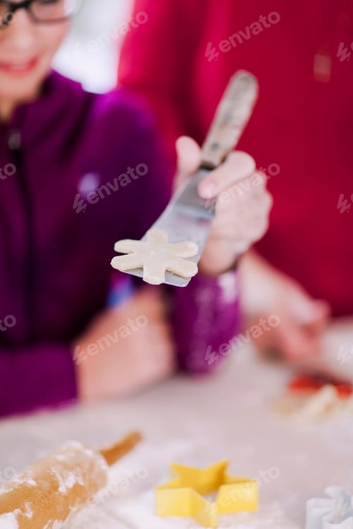 Preview: Close-up of hand holding a cookie cutter with dough