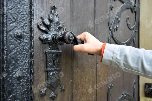 Preview: Man opens an ancient wooden door decorated with wrought iron elements.