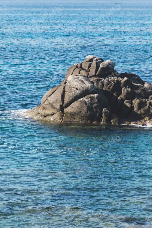 Preview: Wild rocky beach coastline and the sea, wave splashes on rock in sea shore, calm sea. Breaking waves