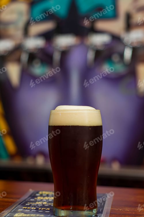 Preview: Vertical closeup of a glass of beer on a wooden table