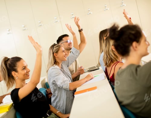 Visualização: Estudantes universitários na sala de aula com as mãos levantadas