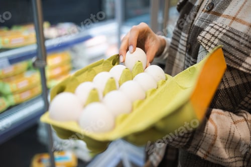 Preview: Close up of female hands choosing eggs in a supermarket.
