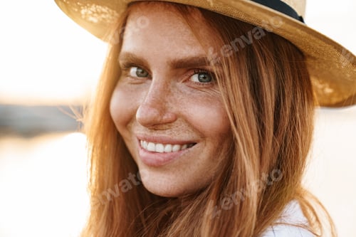 Preview: Image of joyful redhead woman in hat smiling and looking at camera