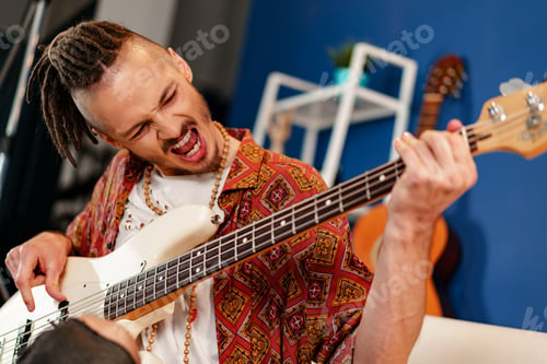 Preview: Young man guitar player sitting and performing on a couch