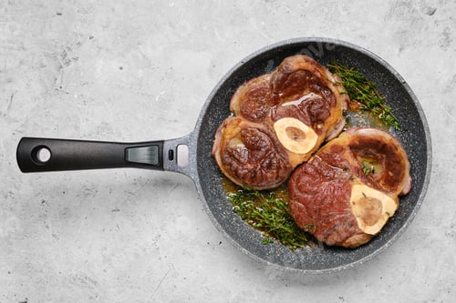 Preview: Two pieces of beef ossobuco in a frying pan with thyme