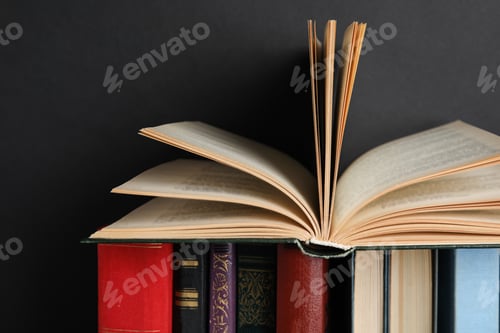 Preview: Different hardcover books against black background, closeup