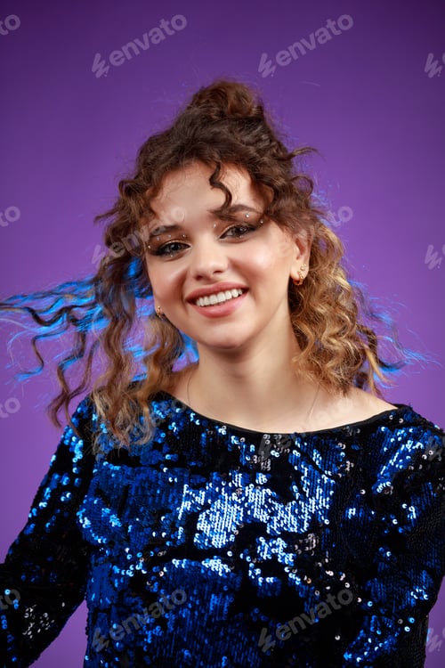 Preview: A vertical portrait of a young curly-haired girl stretching her hair and laughing