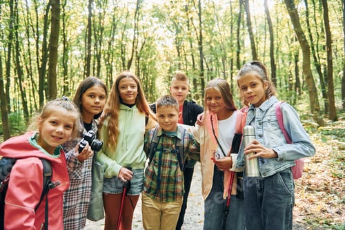 Preview: Standing together. Kids in green forest at summer daytime together