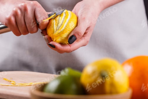 Preview: young woman in a gray aprons cuts lemon zest