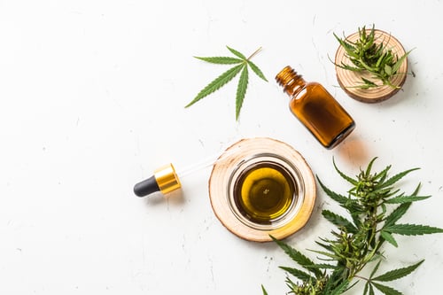 Preview: CBD oil and cannabis leaves at white table