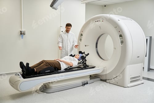 Preview: Handsome doctor guides female patient during MRI scan in modern healthcare setting