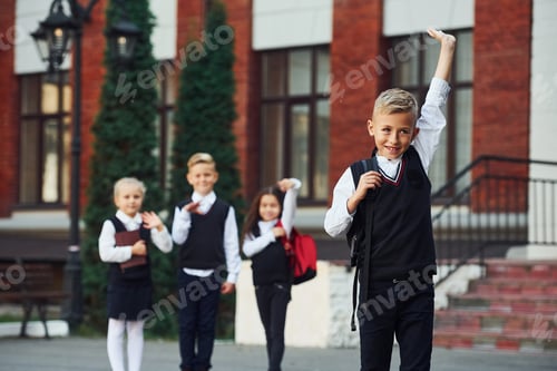 Preview: Group of kids in school uniform posing to the camera outdoors together near education building