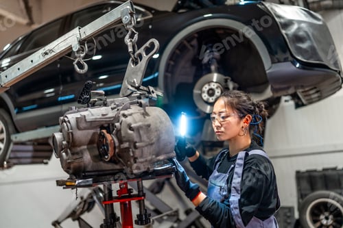 Preview: Female mechanic inspecting gearbox in auto repair shop