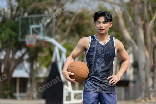 Preview: Portrait of man in activewear holding a ball standing on the basketball court