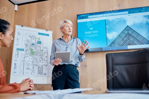 Preview: Mature caucasian businesswoman standing and using a tablet while giving a presentation in the board