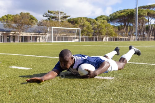 Preview: African American young male athlete scoring a try a rugby ball on a field