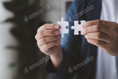 Preview: Man holding two jigsaw puzzles put together, business management concept