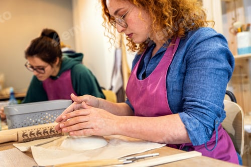 Preview: Woman working in pottery studio workshop making bowl from clay.
