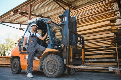 Preview: Warehouse worker sitting on forklift near lumber stacks