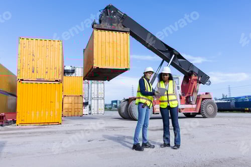 Preview: Two Female Engineers in Safety Vests Oversee a Shipping Yard Operation with a Container Lift Handlin