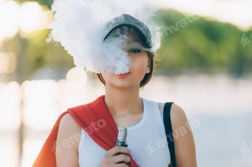 Preview: Pretty young hipster asian woman in black hat vape ecig
