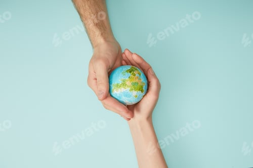 Preview: top view of man and woman holding planet model on turquoise background, earth day concept