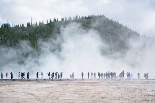 Preview: Tourists exploring a misty geothermal area with a scenic backdrop