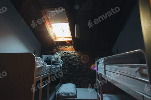 Preview: Man sits in bedroom in hostel with laptop