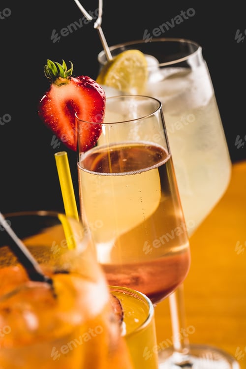 Preview: Vertical shot of champagne and other cocktails in fancy glasses and straws on a table