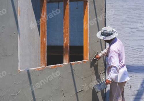Preview: Asian construction worker using trowel to plastering cement wall in house construction site